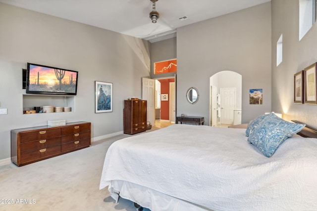 bedroom with a high ceiling, carpet flooring, baseboards, and arched walkways