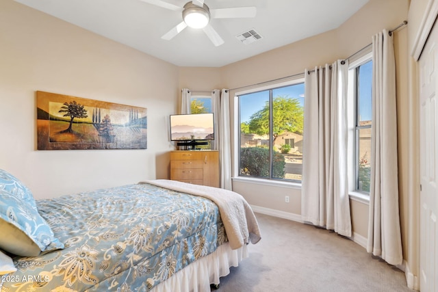 carpeted bedroom with multiple windows, baseboards, a closet, and a ceiling fan