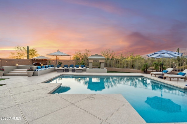 pool at dusk featuring outdoor lounge area, a patio, and fence
