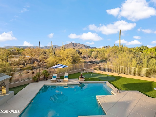 view of pool featuring an area to practice putting, a mountain view, a patio area, and a fenced backyard