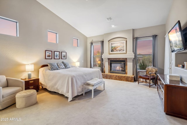bedroom with a glass covered fireplace, vaulted ceiling, multiple windows, and carpet floors