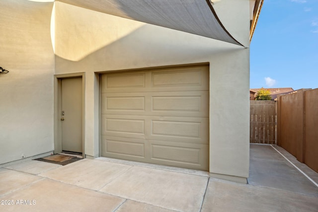 garage with fence and concrete driveway