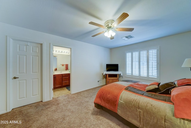 bedroom with a ceiling fan, light colored carpet, visible vents, and ensuite bathroom