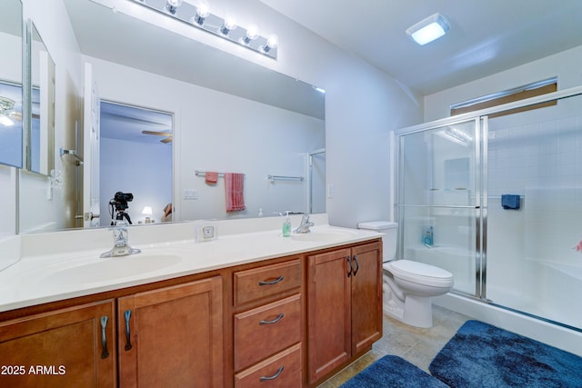 bathroom featuring a shower stall, toilet, double vanity, and a sink