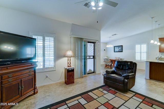 living room with ceiling fan with notable chandelier, visible vents, and baseboards