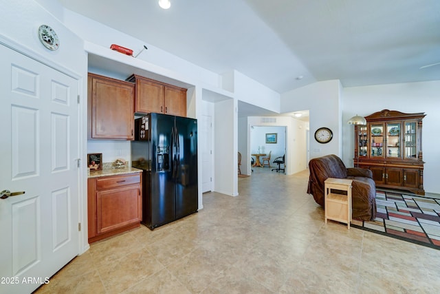 kitchen featuring visible vents, black fridge, light stone counters, open floor plan, and lofted ceiling