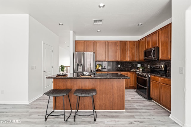 4140 E Claxton Ave, Gilbert, AZ 85297 - kitchen featuring stainless steel appliances, light wood-type flooring, a kitchen island with sink, a breakfast bar, and backsplash