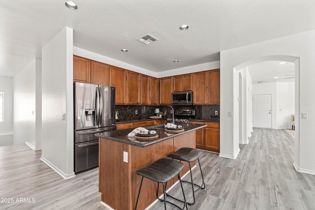 4140 E Claxton Ave, Gilbert, AZ 85297 - kitchen with stainless steel appliances, a sink, arched walkways, a center island with sink, and decorative backsplash