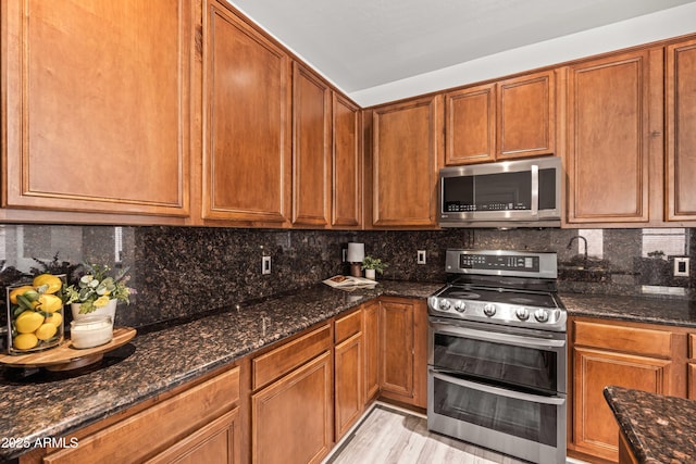 4140 E Claxton Ave, Gilbert, AZ 85297 - kitchen featuring appliances with stainless steel finishes, dark stone countertops, tasteful backsplash, and brown cabinets