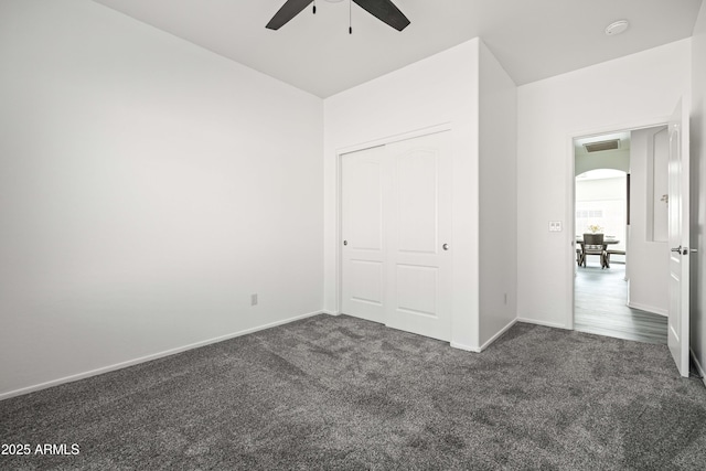 4140 E Claxton Ave, Gilbert, AZ 85297 - unfurnished bedroom featuring dark carpet, arched walkways, baseboards, a ceiling fan, and a closet