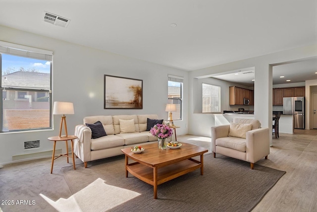 living room featuring light wood finished floors, recessed lighting, and visible vents