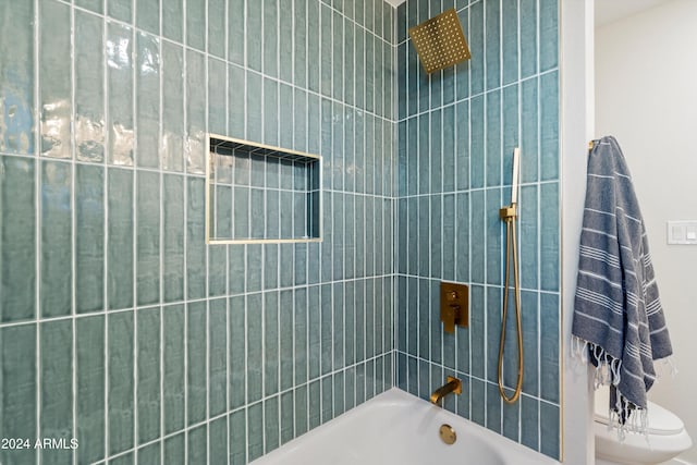 bathroom with toilet and tiled shower / bath