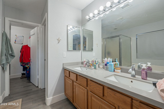 bathroom with hardwood / wood-style floors, vanity, and a shower with door