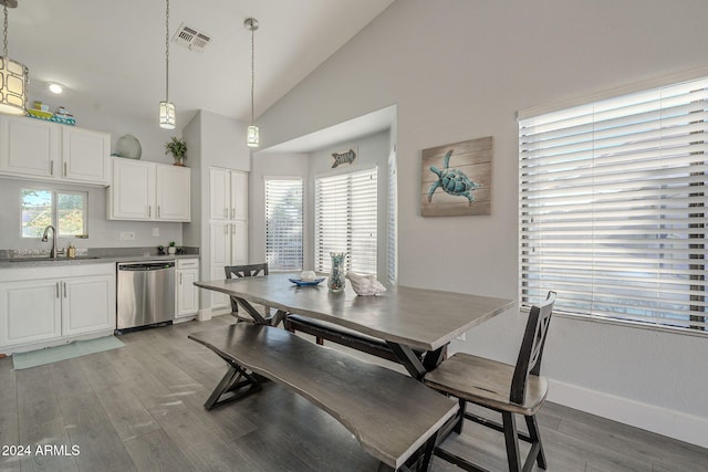 dining area with sink, a healthy amount of sunlight, lofted ceiling, and light hardwood / wood-style floors