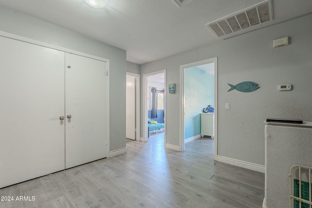 interior space with a textured ceiling and light hardwood / wood-style flooring