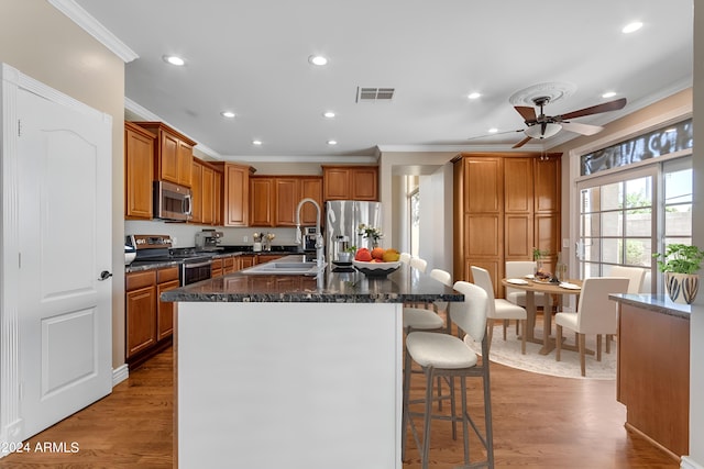 kitchen featuring stainless steel appliances, sink, a kitchen island with sink, and light hardwood / wood-style flooring