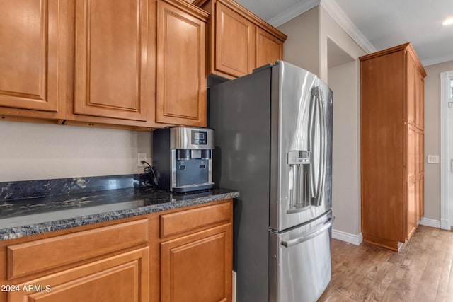 kitchen with light hardwood / wood-style flooring, ornamental molding, dark stone counters, and stainless steel refrigerator with ice dispenser