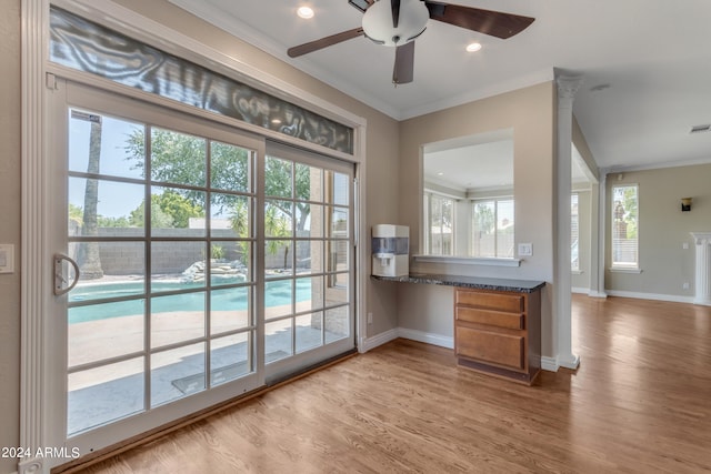 bar featuring dark stone countertops, crown molding, light hardwood / wood-style flooring, and ceiling fan