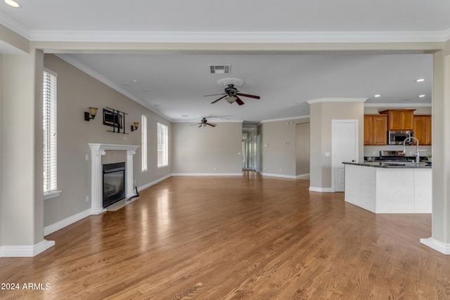 unfurnished living room featuring ceiling fan, crown molding, and light wood-type flooring