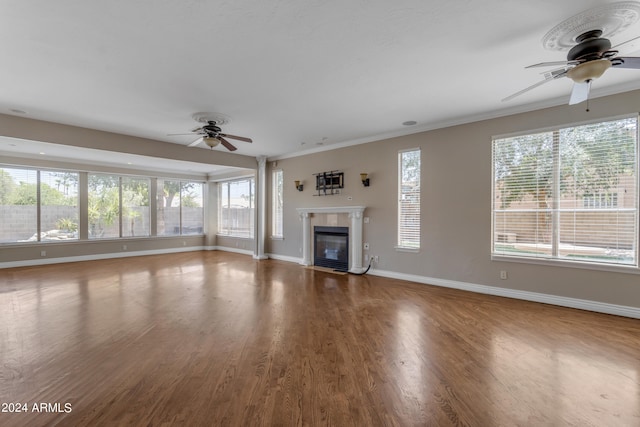 unfurnished living room featuring hardwood / wood-style floors, a wealth of natural light, a tile fireplace, and ceiling fan