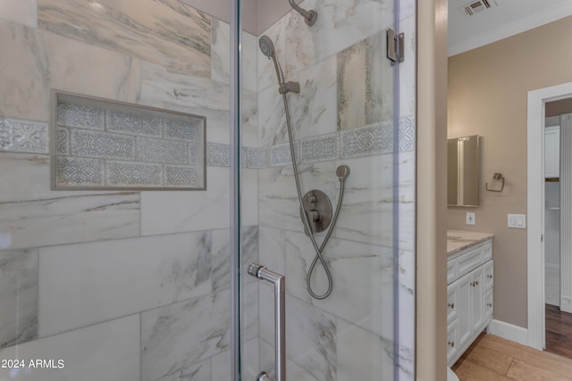 bathroom featuring hardwood / wood-style flooring, vanity, ornamental molding, and a shower with shower door