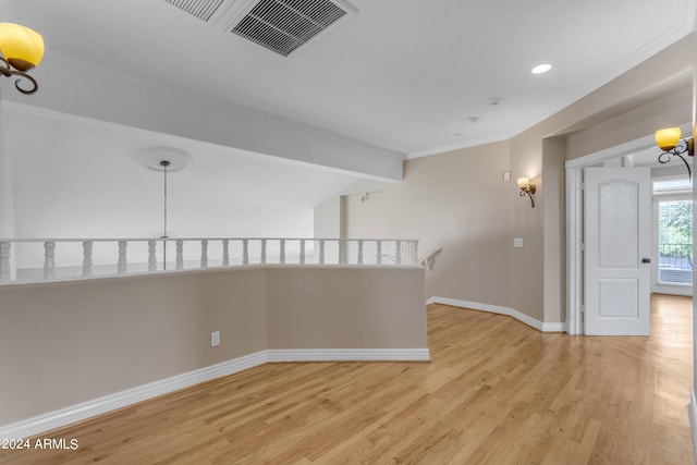 empty room with beam ceiling, crown molding, and light wood-type flooring