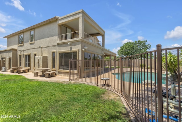 back of house featuring a fenced in pool, a fire pit, a lawn, and a patio