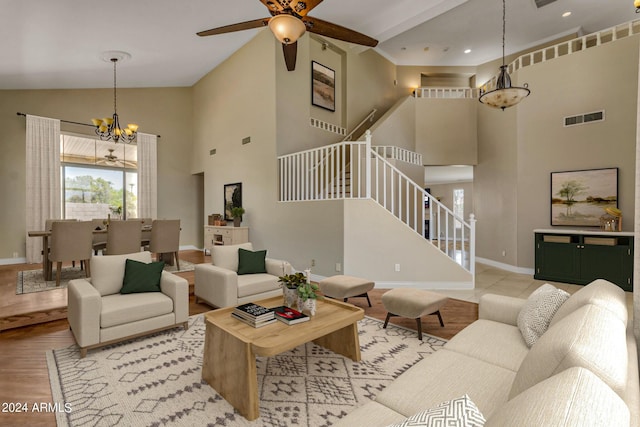 living room with high vaulted ceiling, ceiling fan with notable chandelier, and light hardwood / wood-style floors