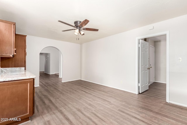 16638 N 46th Ln, Glendale, AZ 85306 - unfurnished living room featuring baseboards, a ceiling fan, arched walkways, and light wood finished floors
