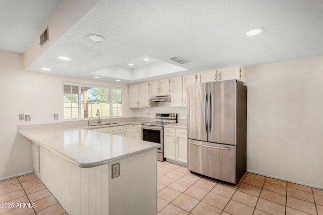 kitchen with under cabinet range hood, stainless steel appliances, a peninsula, visible vents, and light countertops