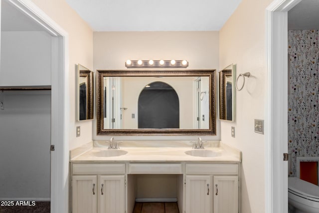 bathroom with double vanity, a sink, and toilet