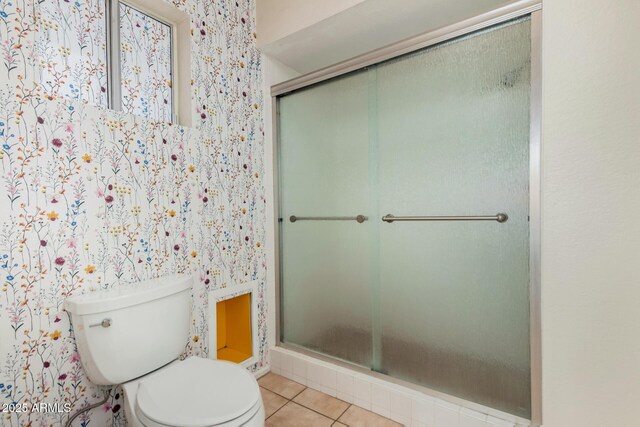 full bath with toilet, wallpapered walls, a shower stall, and tile patterned floors