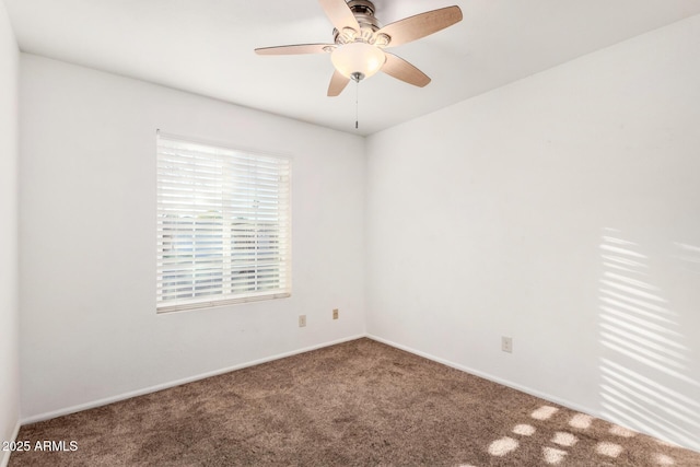 carpeted spare room with a ceiling fan and baseboards