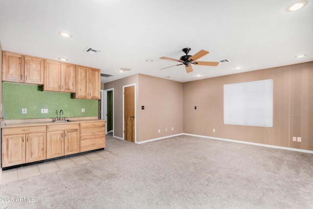 kitchen featuring visible vents, light countertops, light brown cabinetry, light carpet, and a sink