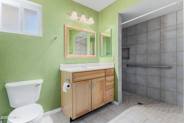 bathroom with tiled shower, vanity, toilet, and tile patterned floors