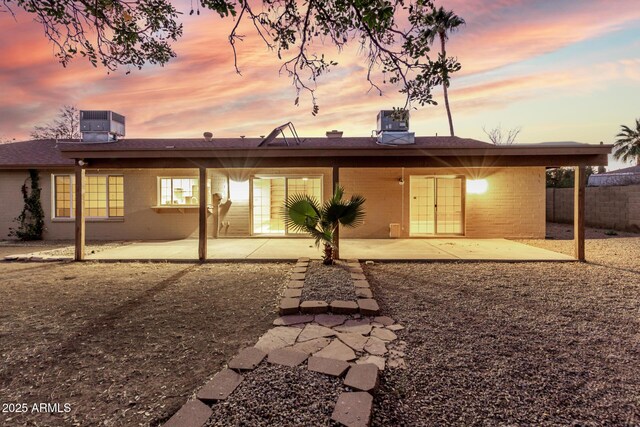 rear view of house featuring a patio area, fence, brick siding, and central AC unit