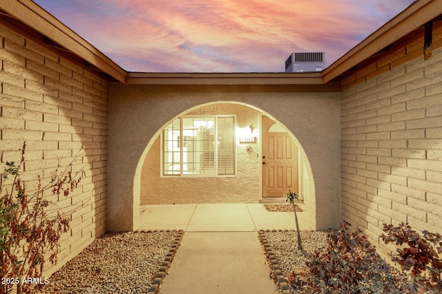 view of exterior entry with cooling unit and stucco siding