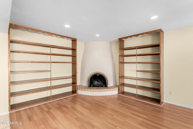 unfurnished living room featuring a fireplace, baseboards, wood finished floors, and recessed lighting