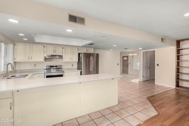 kitchen featuring visible vents, appliances with stainless steel finishes, light countertops, under cabinet range hood, and a sink