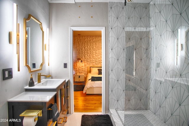 bathroom with tiled shower, wood-type flooring, and vanity