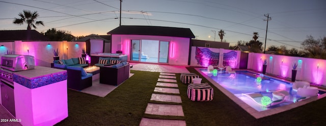 patio terrace at dusk featuring a fenced in pool, area for grilling, an outdoor living space with a fire pit, and exterior kitchen