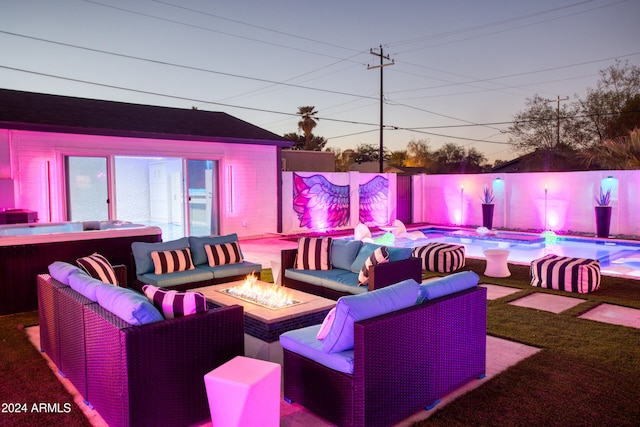 patio terrace at dusk with a swimming pool and an outdoor living space with a fire pit