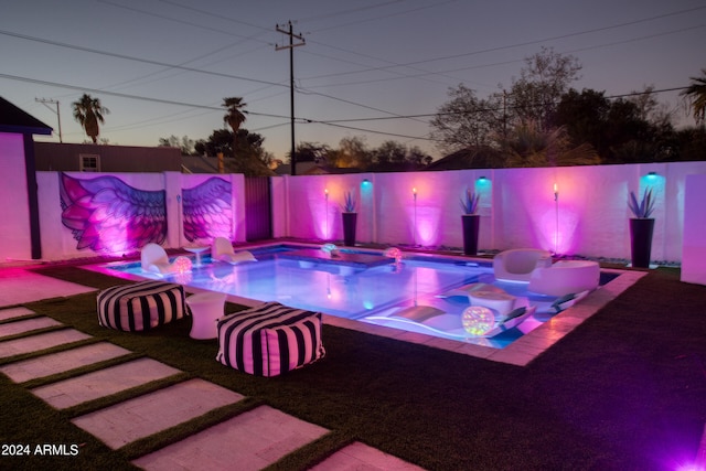 pool at dusk with an in ground hot tub