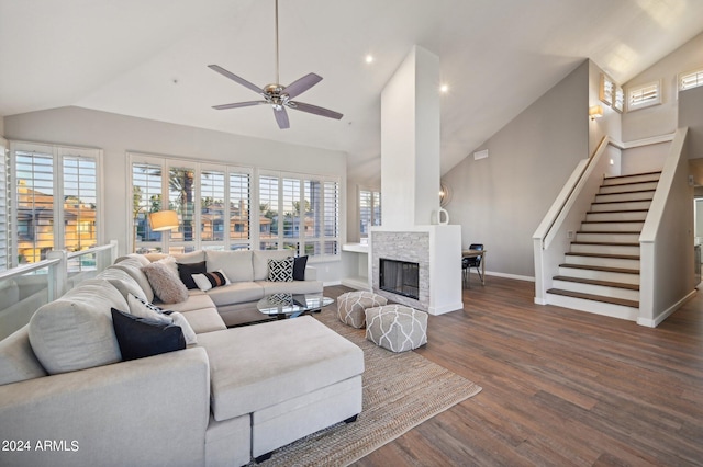 living room featuring a stone fireplace, lofted ceiling, dark wood-type flooring, and ceiling fan