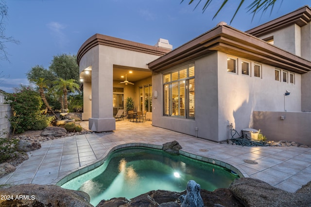 back house at dusk featuring a fenced in pool, ceiling fan, and a patio area