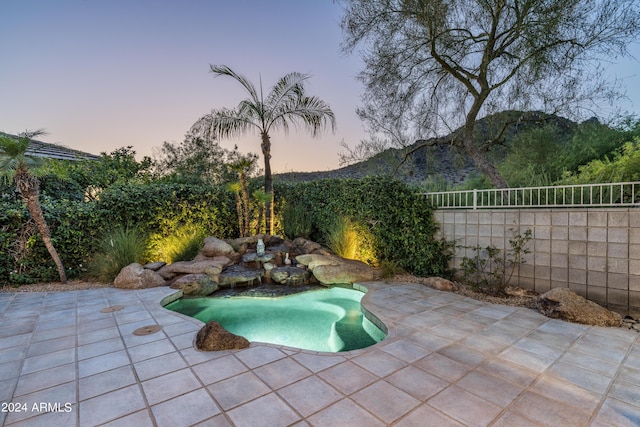 pool at dusk with a mountain view and a patio area