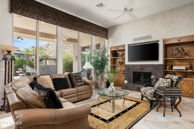 tiled living room featuring a fireplace, ceiling fan, and a healthy amount of sunlight