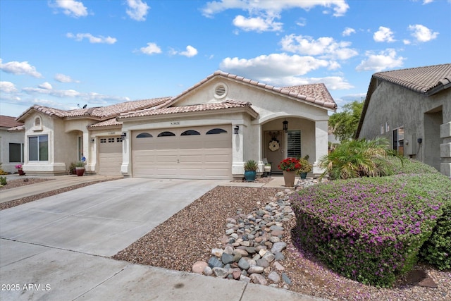 mediterranean / spanish house featuring an attached garage, stucco siding, driveway, and a tile roof