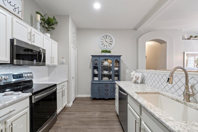 kitchen with appliances with stainless steel finishes, a sink, backsplash, and white cabinets
