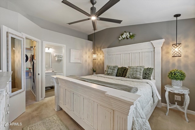 bedroom featuring light carpet, vaulted ceiling, a walk in closet, connected bathroom, and ceiling fan
